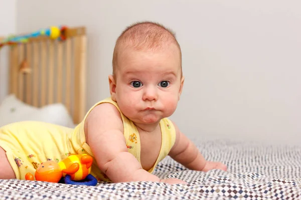Feliz bebé de tres meses acostado en una manta sobre su estómago. Se apoya en sus manos. Mirando a la cámara. Amarillo . —  Fotos de Stock