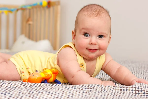 Happy well-fed three months old baby lying on a blanket on his stomach. Leans on his hands. Baby like a boss. Looking at the camera. Yellow. — Stock Photo, Image