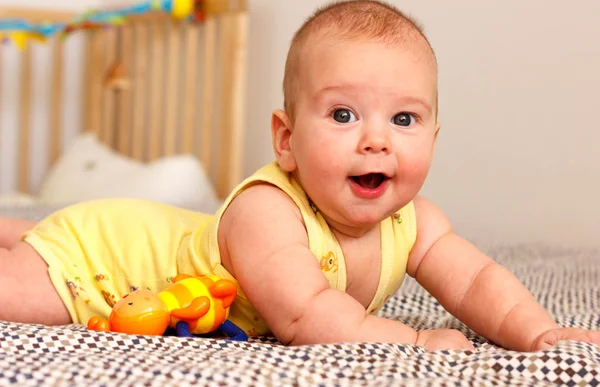 Happy well-fed three months old baby lying on a blanket on his stomach. Leans on his hands. Baby like a boss. Looking at the camera. Yellow. — Stock Photo, Image