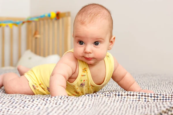 Happy well-fed three months old baby lying on a blanket on his stomach. Leans on his hands. Baby like a boss. Yellow. — Stock Photo, Image