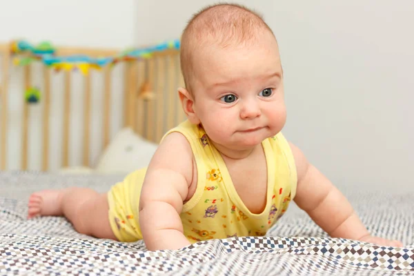 Feliz bebé de tres meses bien alimentado acostado sobre una manta en el estómago. Se apoya en sus manos. Bebé como un jefe. Amarillo . — Foto de Stock