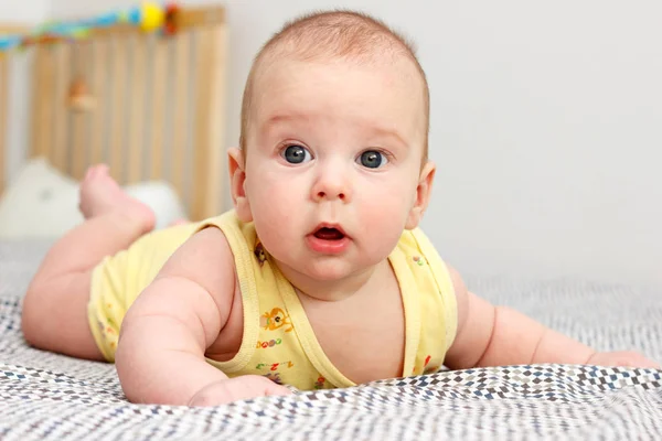 Happy well-fed three months old baby lying on a blanket on his stomach. Leans on his hands. Baby like a boss. Looking at the camera. Yellow. — Stock Photo, Image