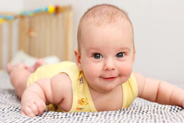 Happy well-fed three months old baby lying on a blanket on his stomach. Leans on his hands. Baby like a boss. Looking at the camera. Yellow. — Stock Photo, Image