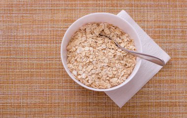 Sağlıklı kahvaltı için gunny arka plan üzerinde beyaz peçete üzerinde ham yulaf ezmesi ile Fincan