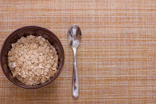 Cup with raw oatmeal on gunny background for healthy breakfast on top with with and copy space — Stock Photo, Image