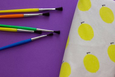 Mor arka plan üzerinde fırçalar ve kalem kutusu. Okula geri dön. Üstte görüntüle ve kopyalama alanı