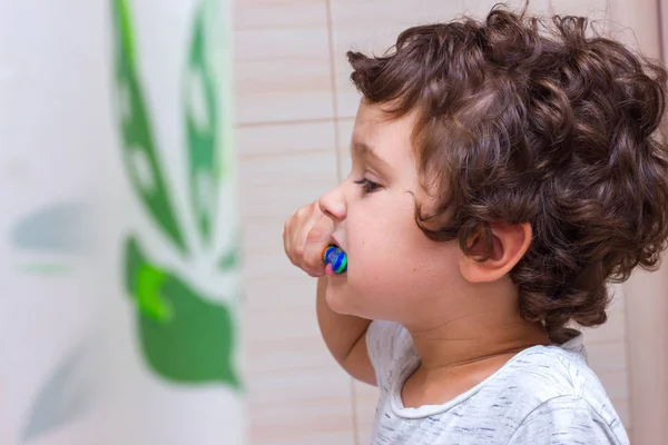 Niño pequeño cepillándose los dientes en el baño delante del espejo, higiene bucal — Foto de Stock