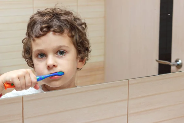 Niño pequeño cepillándose los dientes en el baño delante del espejo, higiene bucal —  Fotos de Stock