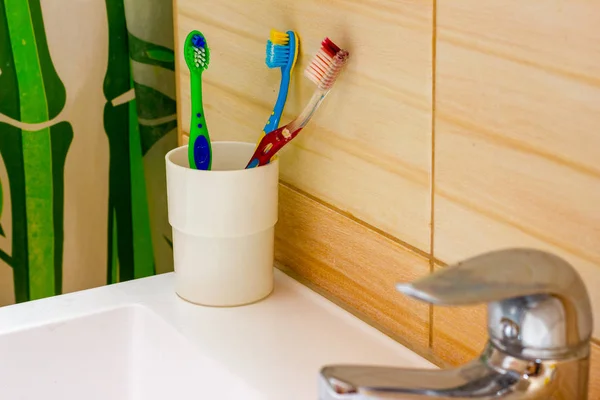 Cepillos de dientes de pie en el lavabo en la pared del baño —  Fotos de Stock