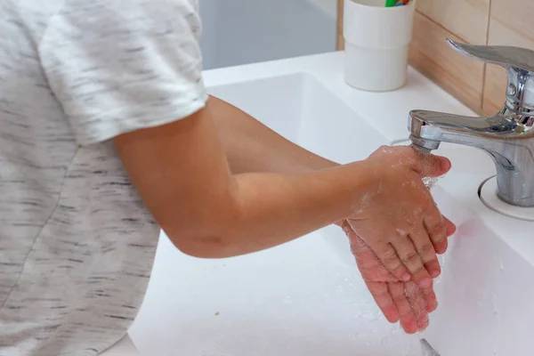 Хлопчик у легкій футболці миє руки з милом. Гігієна рук — стокове фото