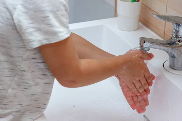 Boy in a light T-shirt washes his hands with soap. Hand hygiene — Stock Photo, Image