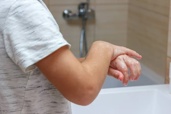 Un chico con una camiseta ligera se lava las manos con jabón. Higiene manos —  Fotos de Stock