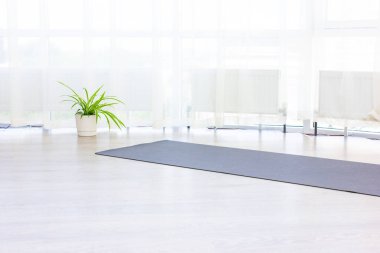gray rug for practicing yoga in large bright gym studio ang green flowers. clipart