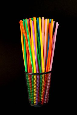 Dik Siyah Ağ Holder 'da Renkli İçen Çubuklar Dikey. Siyah Arkaplanda Ağ Tutucusunda Renkli Plastik İçme Çubukları.