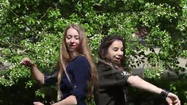 Две Девушки Соревнуются Танце Фоне Зеленой Листвы Молодые Женщины Дурачатся — стоковое видео