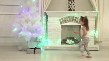 küçük bir kız iki kuyruklu bir hediye bir şömine ve bir Noel ağacı arka plan üzerinde açar