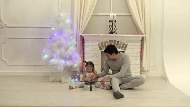 남자가 소녀에 선물을 벽난로 크리스마스 나무와 랜드의 배경에 그것을 방법을 — 비디오
