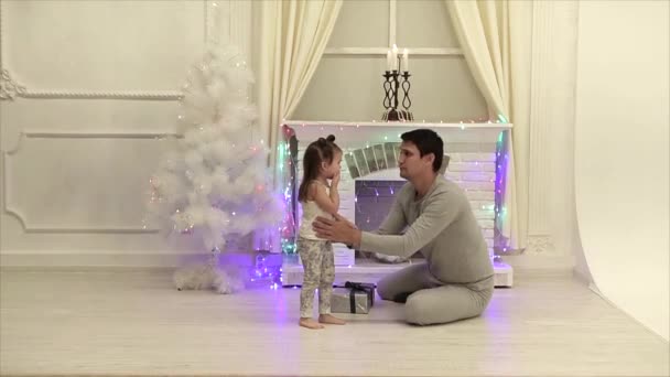 爸爸安慰哭泣的女儿在壁炉和圣诞树的背景下 — 图库视频影像