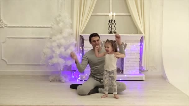 男人和小女孩与两个尾巴跳舞有趣的壁炉和圣诞树的背景 — 图库视频影像