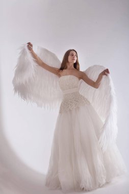 Melek kanatları beyaz arka plan üzerinde beyaz elbiseli kız. Angel-kadın