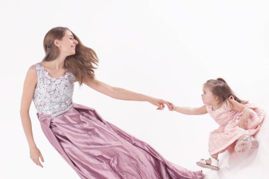 Anne ve çocuk beyaz bir arka plan üzerinde poz. Kadın ve kız pembe elbisesi oyunu