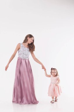 Anne ve çocuk beyaz bir arka plan üzerinde poz. Kadın ve kız pembe elbisesi oyunu
