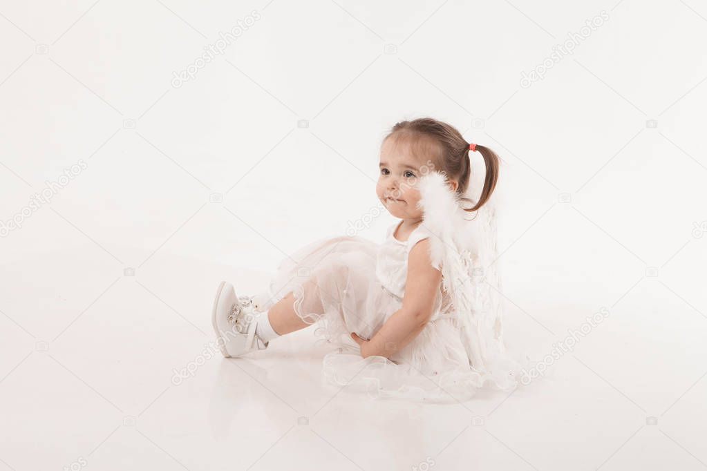 little girl in white dress with wings playing on white background