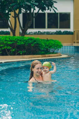 genç anne ve üzerinde güneş tatil yüzme havuzunda oynayan kız