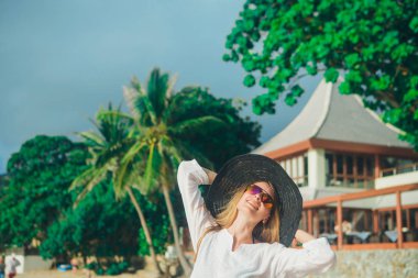 Plaj arka plan üzerinde şapkalı yakışıklı kız. Beyaz giysiler ve balck şapka bir kadın portresi