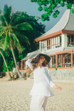 gözlük ve şapka plaj arka plan üzerinde olan yakışıklı kız. Beyaz giysiler ve balck şapka bir kadın portresi