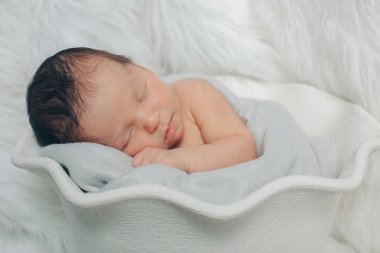 Küçük bir çocuk beyaz sepet içinde yatıyor