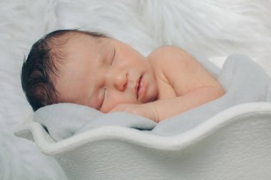 Küçük bir çocuk beyaz sepet içinde yatıyor