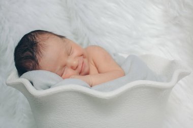 Küçük bir çocuk beyaz sepet içinde yatıyor