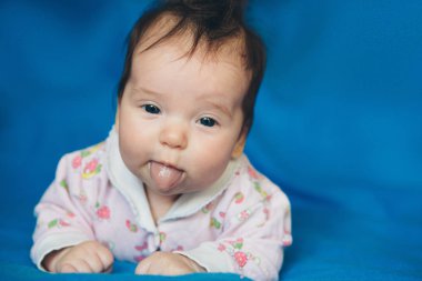 Yeni doğan bebeğin karnına tükürük içinde onun ağız mavi arka plan üzerinde yatan