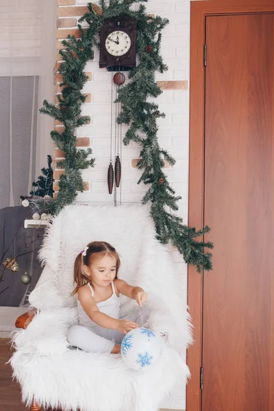 Una Niña Sentada Una Silla Con Una Bola Blanca Navidad —  Fotos de Stock