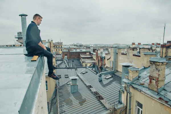 handsome man sitting on the edge of the roof