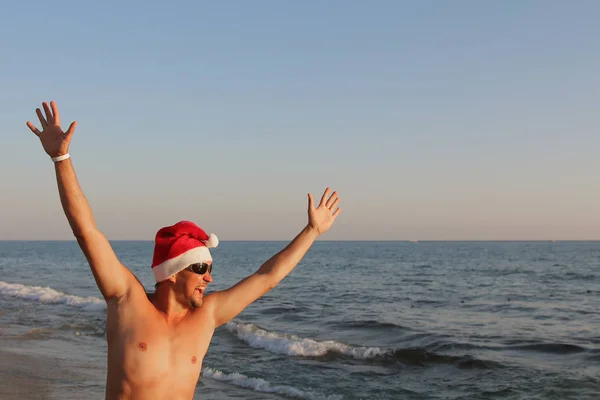 Чоловік Червоній Різдвяній Шапці Сонцезахисних Окулярах Своїми Руками Проти Моря — стокове фото