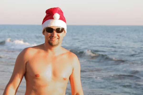 Portret Człowieka Czerwony Kapelusz Boże Narodzenie Okulary Przeciwsłoneczne Morzem — Zdjęcie stockowe