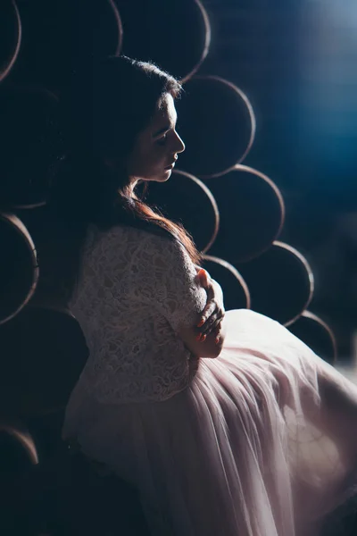 March 8: beautiful girl in a light dress with bouquet of flowers among metal pipes — Stock Photo, Image