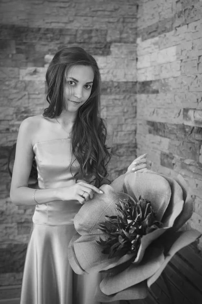 8 de marzo: hermosa chica con el pelo largo junto a una enorme flor artificial — Foto de Stock
