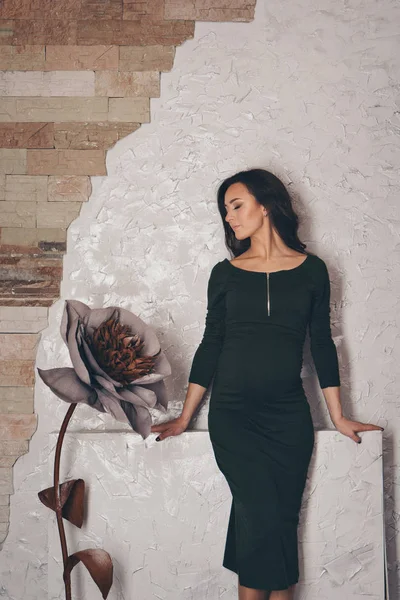 8. března: krásná těhotná dívka s dlouhými vlasy vedle obrovské umělé květiny — Stock fotografie