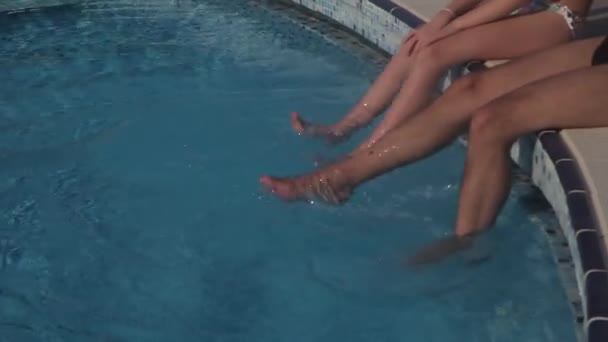 男と女がプールの水で自分の足をブラブラ — ストック動画