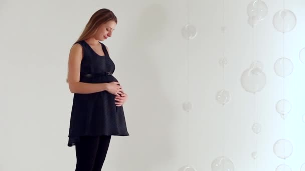 Schwangere Schwarzen Kleid Streicht Sich Über Ihren Bauch Auf Weißem — Stockvideo