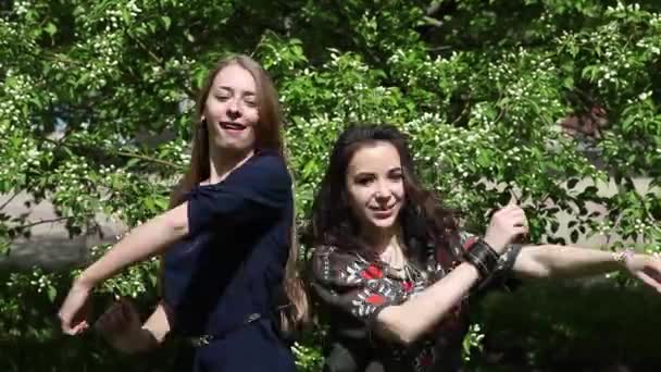 Две Девушки Соревнуются Танце Фоне Зеленой Листвы Молодые Женщины Дурачатся — стоковое видео