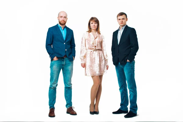 Business development concept: three people looking forward on a white background. Three attractive business people in suits stand next to each other all facing forward