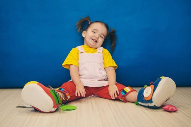 iki kuyrukları ve büyük ayakkabı katta oturan küçük bir kız