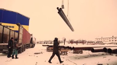Metal boru kamyona yükleniyor. bir büyük santral Vinci kişi metal bir depoda çalışıyor.