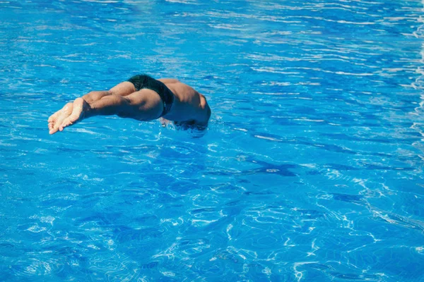 Een man springt in het zwembad. Zwemmer in het water — Stockfoto