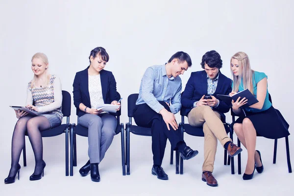 business people waiting in queue sitting in row holding smartphones and cvs, human resources, employment and hiring concept