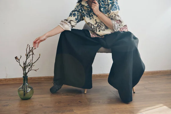 women\'s feet in linen clothes in japanese and shoes next to a flower on a white background